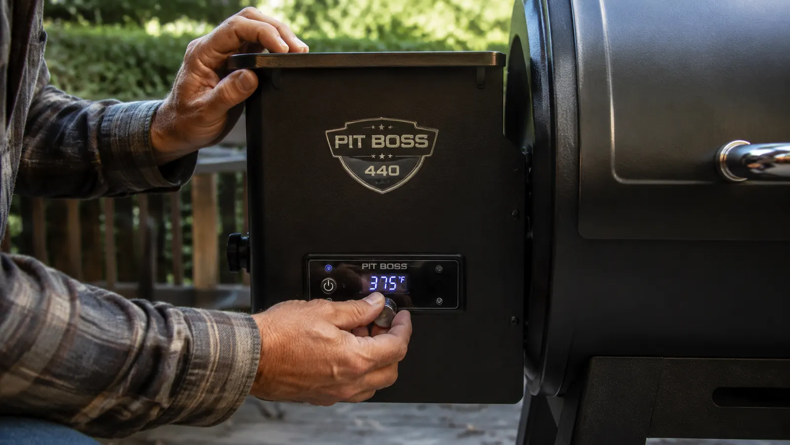 Hand adjusting the digital temperature dial on a Pit Boss pellet grill controller